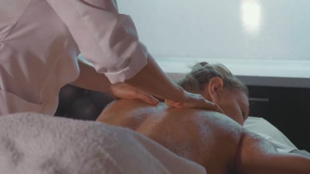 Spa therapeut scrub toe te passen op jonge vrouw terug op luxe beauty salon. — Stockvideo