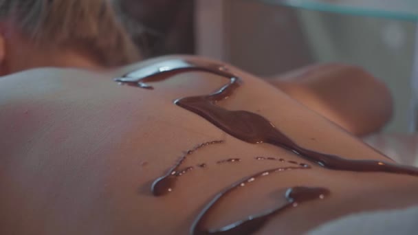 Spa therapeut gieten hete chocolade op jonge vrouw terug op luxe beauty salon — Stockvideo