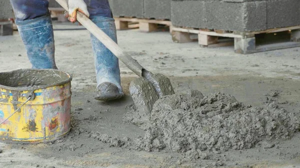 Pekerja menyekop mencampur beton dan memasukkannya ke dalam ember di lokasi konstruksi . — Stok Foto