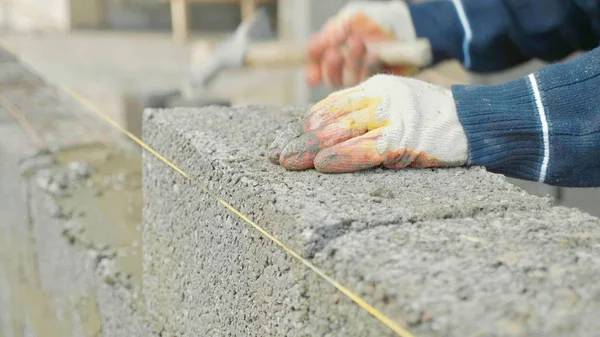 Ouvrier de la construction construit un mur de briques, vue rapprochée sur le chantier de construction — Photo