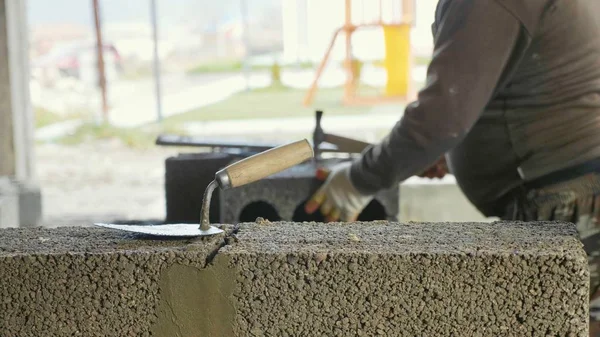 Pembangun bekerja dengan blok konstruksi dengan sekop di latar depan — Stok Foto
