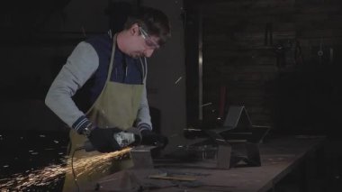 Metal açılı taşlama, ağır çekim üzerinden bir atölyede çalışan demirci.