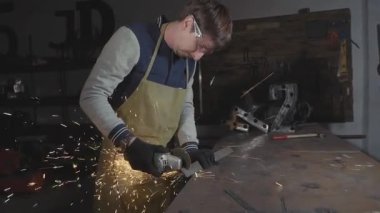 Metal açılı taşlama, ağır çekim üzerinden bir atölyede çalışan demirci.