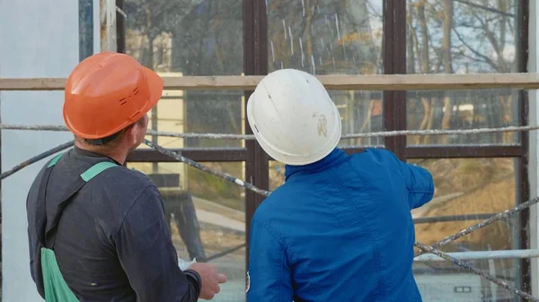 Pekerja konstruksi dan insinyur berbicara di lokasi konstruksi, pandangan belakang . — Stok Foto