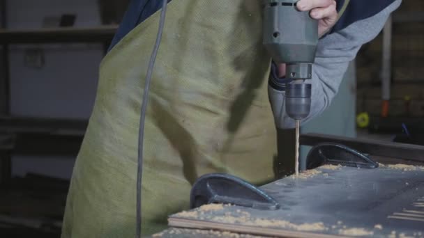 Vista lateral del carpintero perforando un tablón de madera, primer plano cámara lenta . — Vídeos de Stock