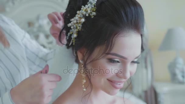 Стилист вставляет вуаль в волосы невесты перед свадьбой — стоковое видео