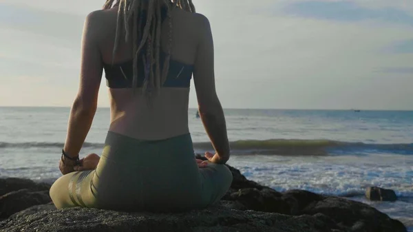 Prática de ioga ao pôr do sol. Yong mulher meditar em lótus posar na praia — Fotografia de Stock