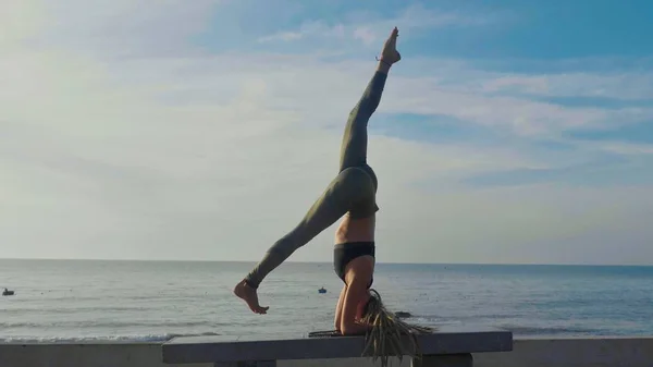 Практика йоги на закате. Yong woman doing yoga exercise on the beach — стоковое фото