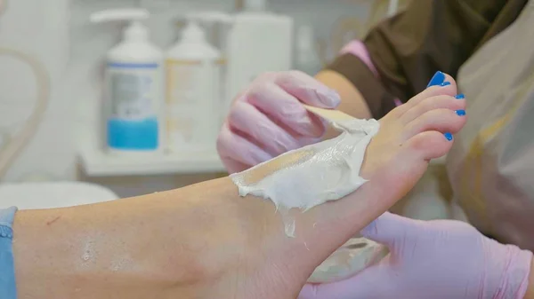 Estetista applicando crema idratante prima di massaggio ai piedi al salone di bellezza spa — Foto Stock