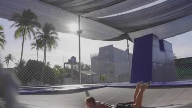 Trambolin üzerinde atlama ve yavaş hareket yapan profesyonel jimnastikçi