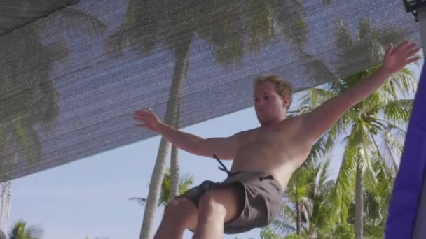 Профессиональный гимнаст прыгает на батуте и делает трюки в замедленной съемке — стоковое видео