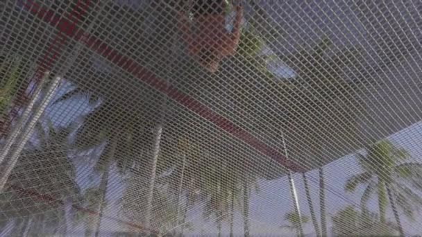 Een weergave onder de trampoline als een man in korte broek en blote kern daarop springt — Stockvideo