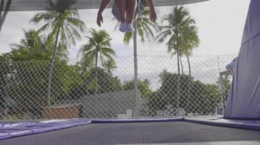 Trambolin üzerinde atlama ve yavaş hareket yapan profesyonel jimnastikçi