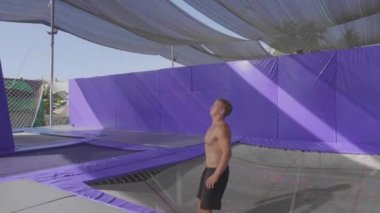 Trambolin üzerinde atlama ve yavaş hareket yapan profesyonel jimnastikçi