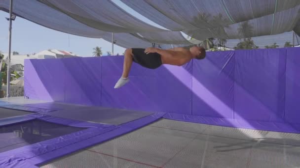 Профессиональный гимнаст прыгает на батуте и делает трюки в замедленной съемке — стоковое видео