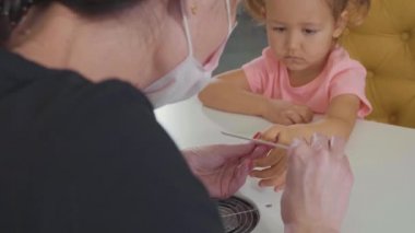 Küçük bebek kız güzellik spa salonu manikür yaparken güzellik uzmanı. .
