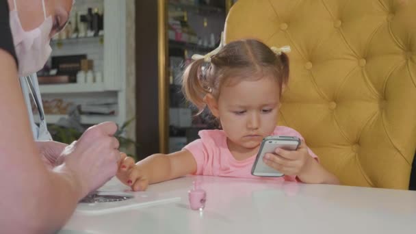 Косметик наносит лак для ногтей на детские ногти в маникюрный салон в замедленной съемке . — стоковое видео