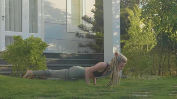 Професійне виконання асан-йоги молодою дівчиною на задньому дворі її будинку — стокове відео