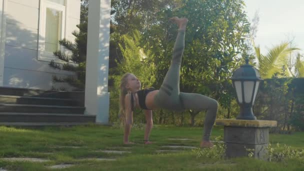 Professionell prestanda av asana yoga av en ung flicka på bakgården av hennes hus — Stockvideo