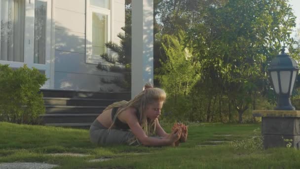 Профессиональное исполнение асаной йоги молодой девушкой на заднем дворе ее дома — стоковое видео