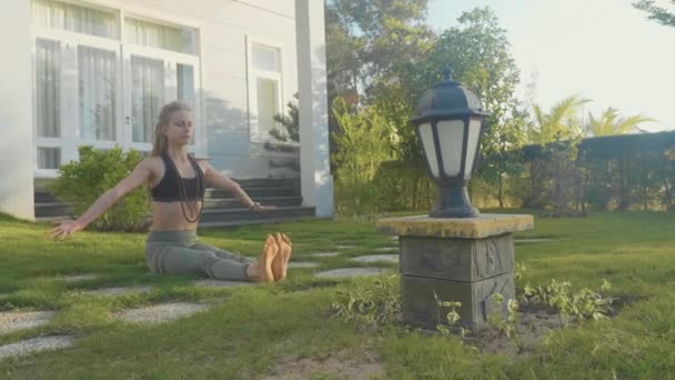 Realización profesional de asana yoga por una joven en el patio trasero de su casa — Vídeos de Stock