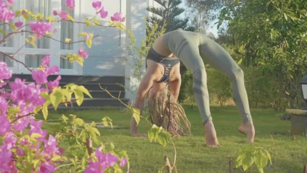 Desempenho profissional de asana ioga por uma jovem no quintal de sua casa — Vídeo de Stock