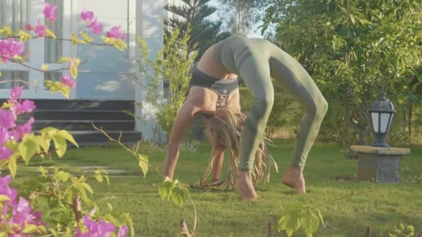 Professionell prestanda av asana yoga av en ung flicka på bakgården av hennes hus — Stockvideo