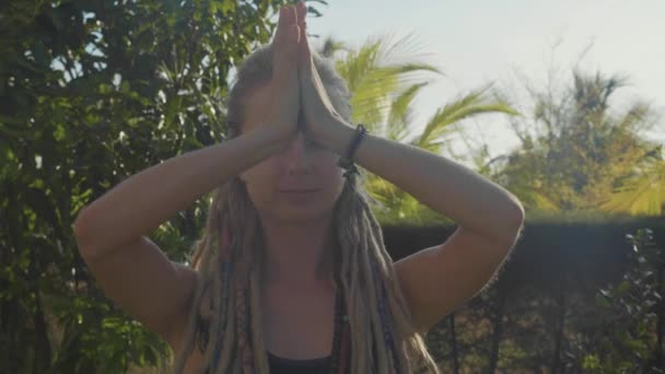 Jonge vrouw doet asana yoga met namaskar gebaar in de achtertuin van haar huis — Stockvideo