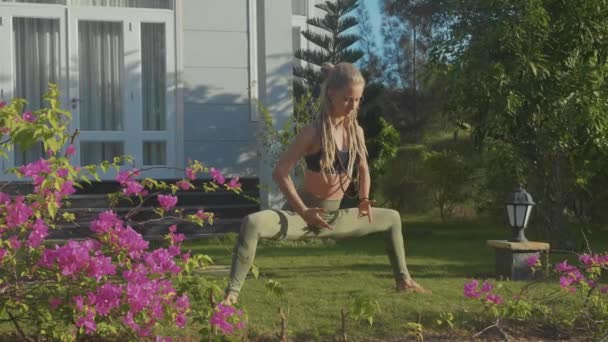 Professionell prestanda av asana yoga av en ung flicka på bakgården av hennes hus — Stockvideo