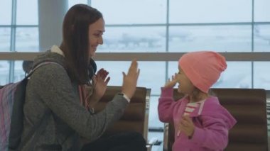 Yound anne ve küçük şirin kız ağır çekimde havaalanında eğleniyor.