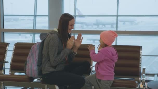 Mutter und kleine süße Tochter amüsieren sich am Flughafen in Zeitlupe. — Stockvideo