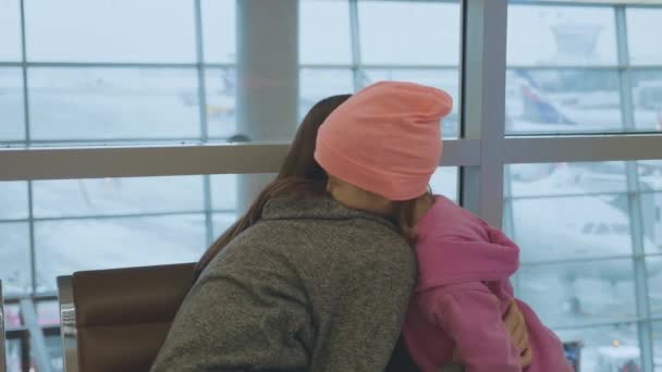 Yound moeder en beetje schattige dochter omarmen zachtjes op de luchthaven in slow motion. — Stockvideo