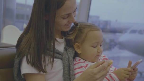 Mãe alimenta sua filha com tangerina no aeroporto em câmera lenta — Vídeo de Stock