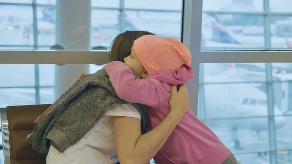 Мама с маленькой симпатичной дочкой нежно обнимаются в аэропорту . — стоковое фото