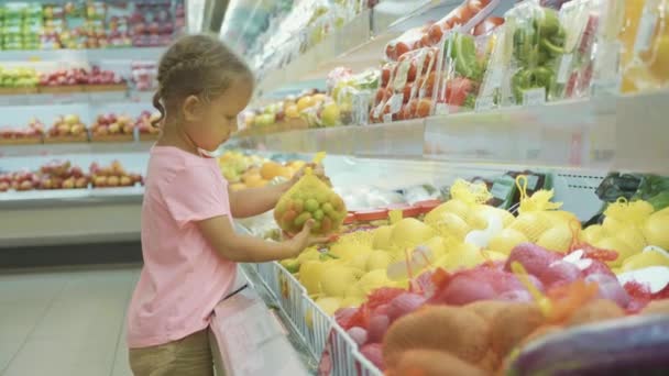 Little cute child girl choosing vegetables in grocery store — Stock Video