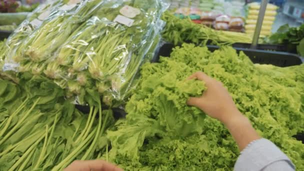 Jovem selecionando vegetais verdes no supermercado — Vídeo de Stock