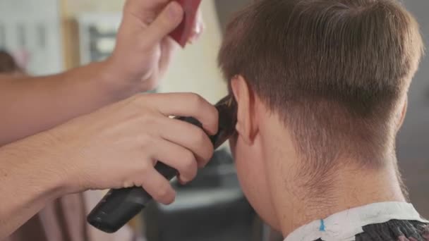 Peluquero macho hace corte de pelo con afeitadora eléctrica, en cámara lenta . — Vídeo de stock