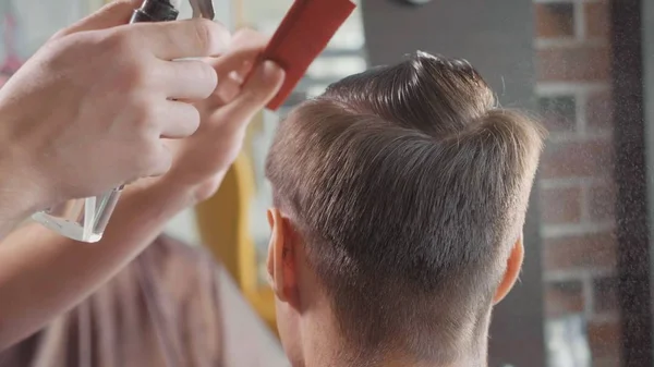 Крупный план парикмахера брызгает воду на волосы клиентов перед стрижкой . — стоковое фото