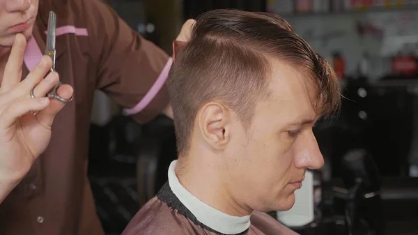 Primer plano del peluquero corta el cabello con tijeras en la barbería .. —  Fotos de Stock