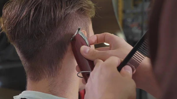 Peluquero macho hace corte de pelo con maquinilla de afeitar eléctrica, primer plano . —  Fotos de Stock