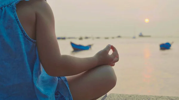 Niña linda medita en pose turca en primera línea de mar — Foto de Stock