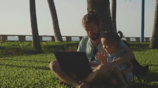 Padre con la niña linda usando el ordenador portátil juntos en el parque en cámara lenta . — Vídeo de stock