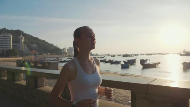 Sportif kadın gündoğumu ağır çekimde, deniz kıyısında koşu — Stok video