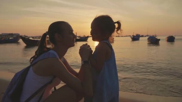 Suave retrato de la joven madre con su pequeña hija en la playa al atardecer . — Vídeos de Stock