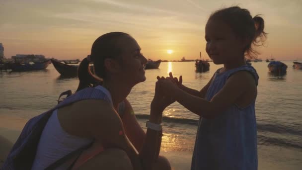 Zachte portret van de jonge moeder met haar dochtertje op het strand bij zonsondergang. — Stockvideo