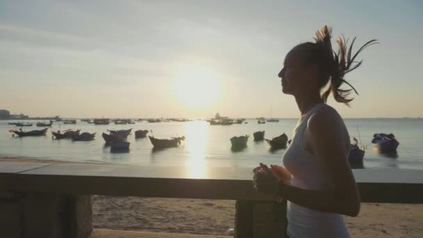 Sportieve jongedame joggen op de kust bij zonsopgang in slow motion — Stockvideo