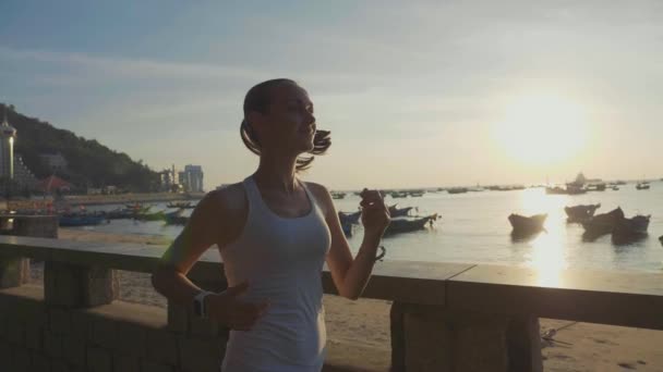 Молодая спортсменка бегает на набережной на рассвете в замедленной съемке — стоковое видео