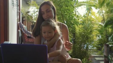 Dizüstü bilgisayar birlikte ağır çekimde kullanarak küçük şirin kızı olan kadın