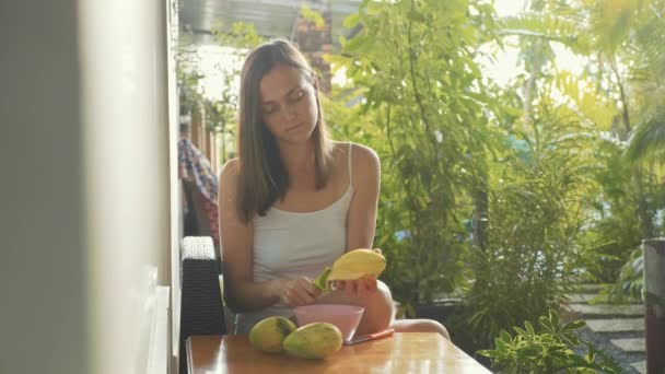 若い女性がスローモーションで美しい庭にマンゴーをクリーンアップします。 — ストック動画
