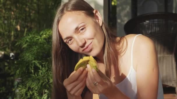 Portrait of happy young woman eats mango with pleasure at green garden — Stock Video